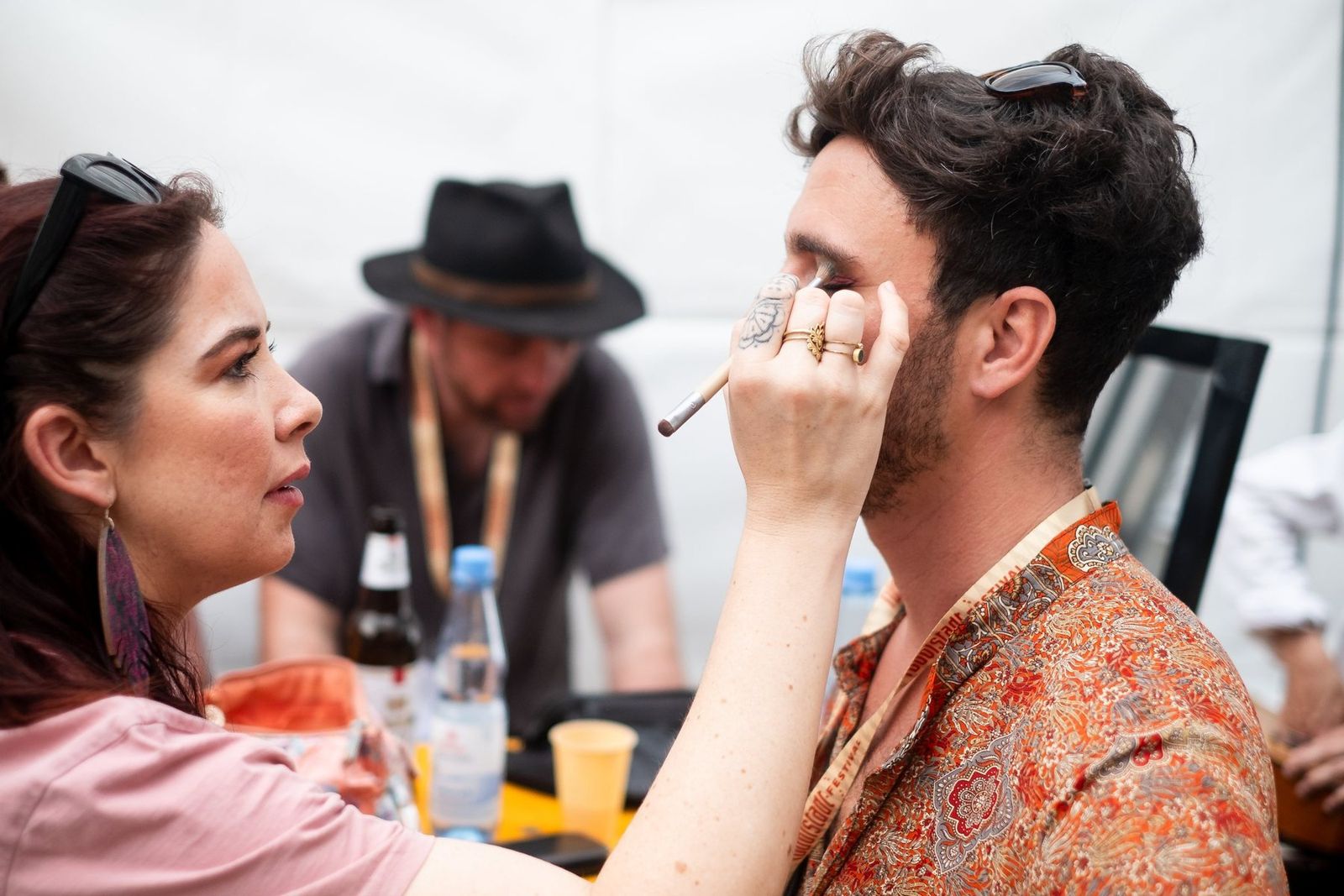 A band member doing another band member’s make-up at the backstage table