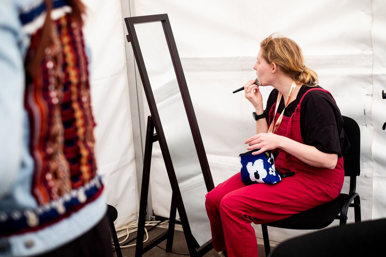 A band member doing her make-up at a mirror in the backstage tent