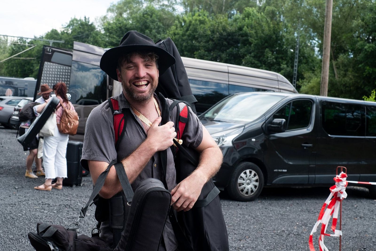 A band member grinning as he unloads the van, cases strapped to his back