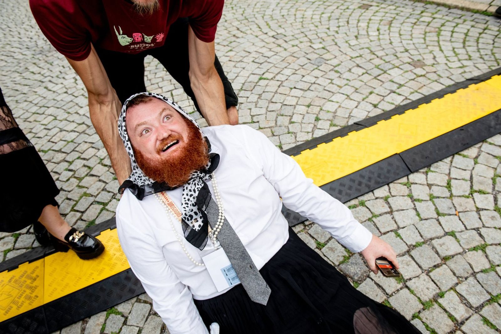 A band member lying on the cobblestones, laughing