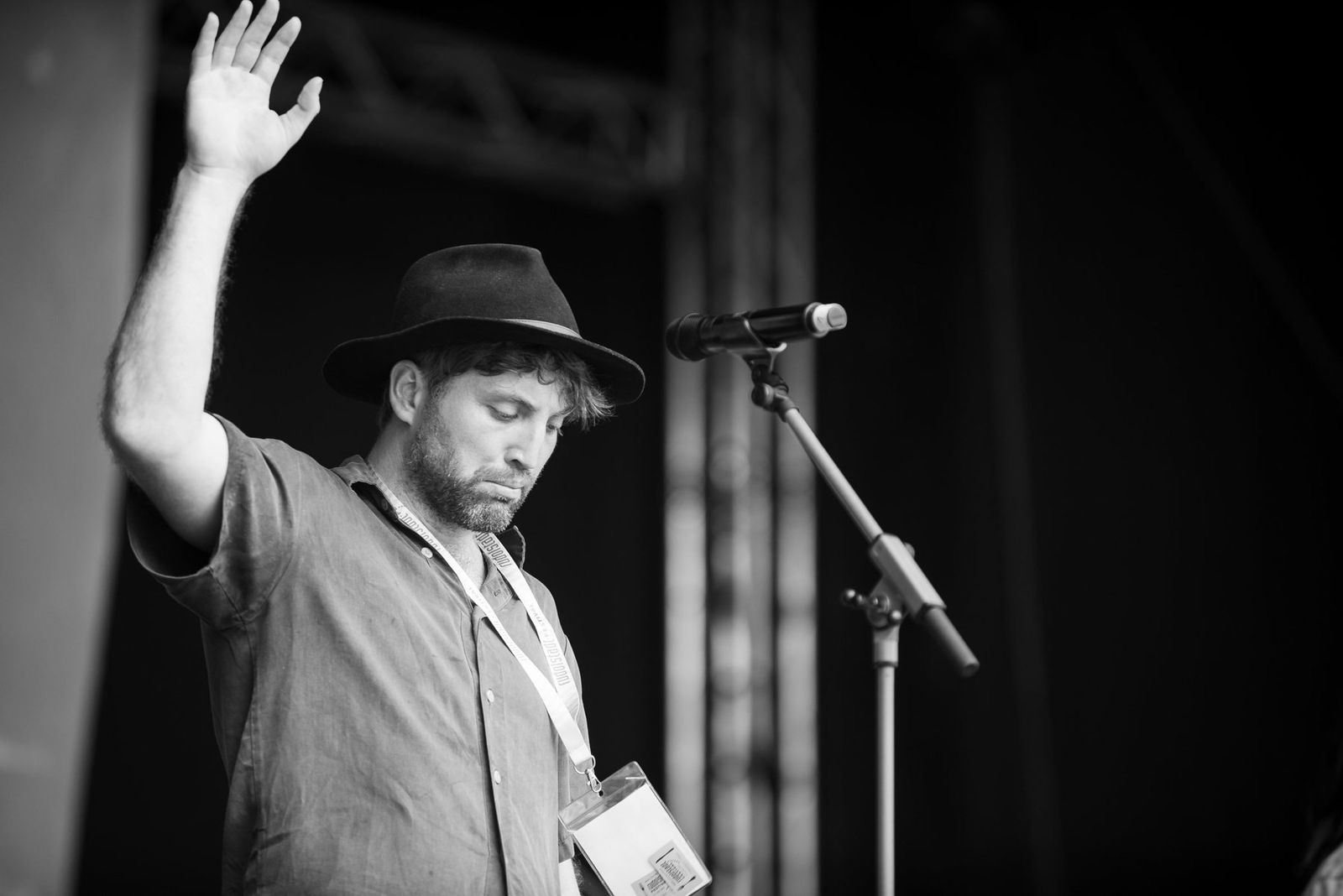 A band member with his hand raised at the side of the stage, black and white