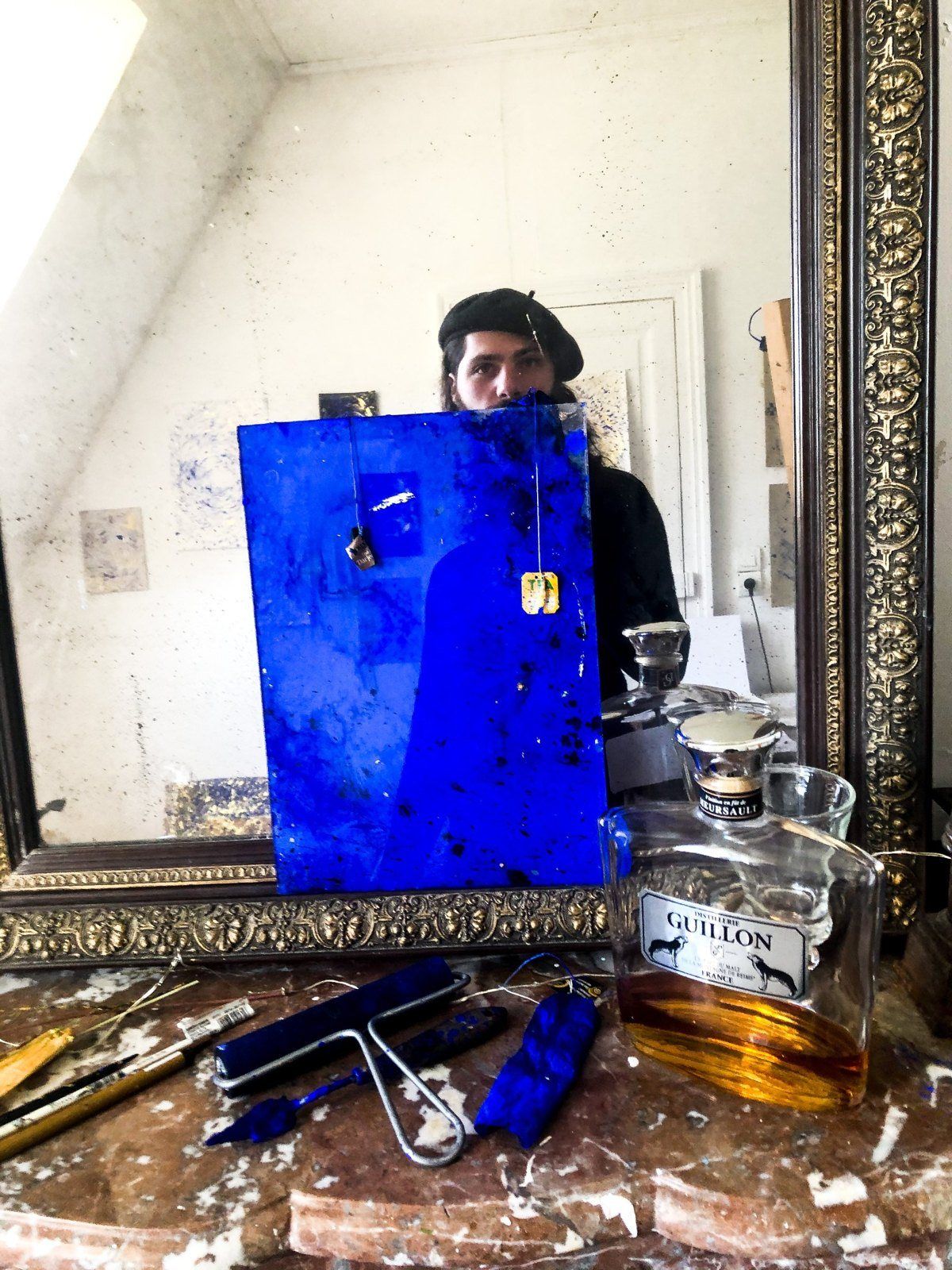 A blue painting held up in front of a gilt mirror