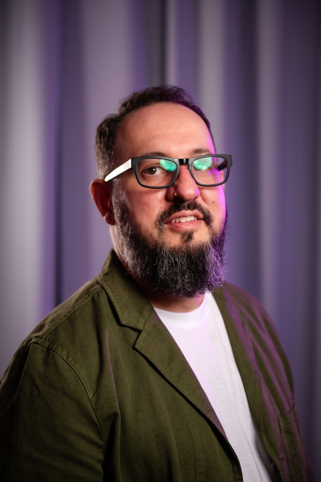 Event portrait: a guest in a green jacket against a purple curtain