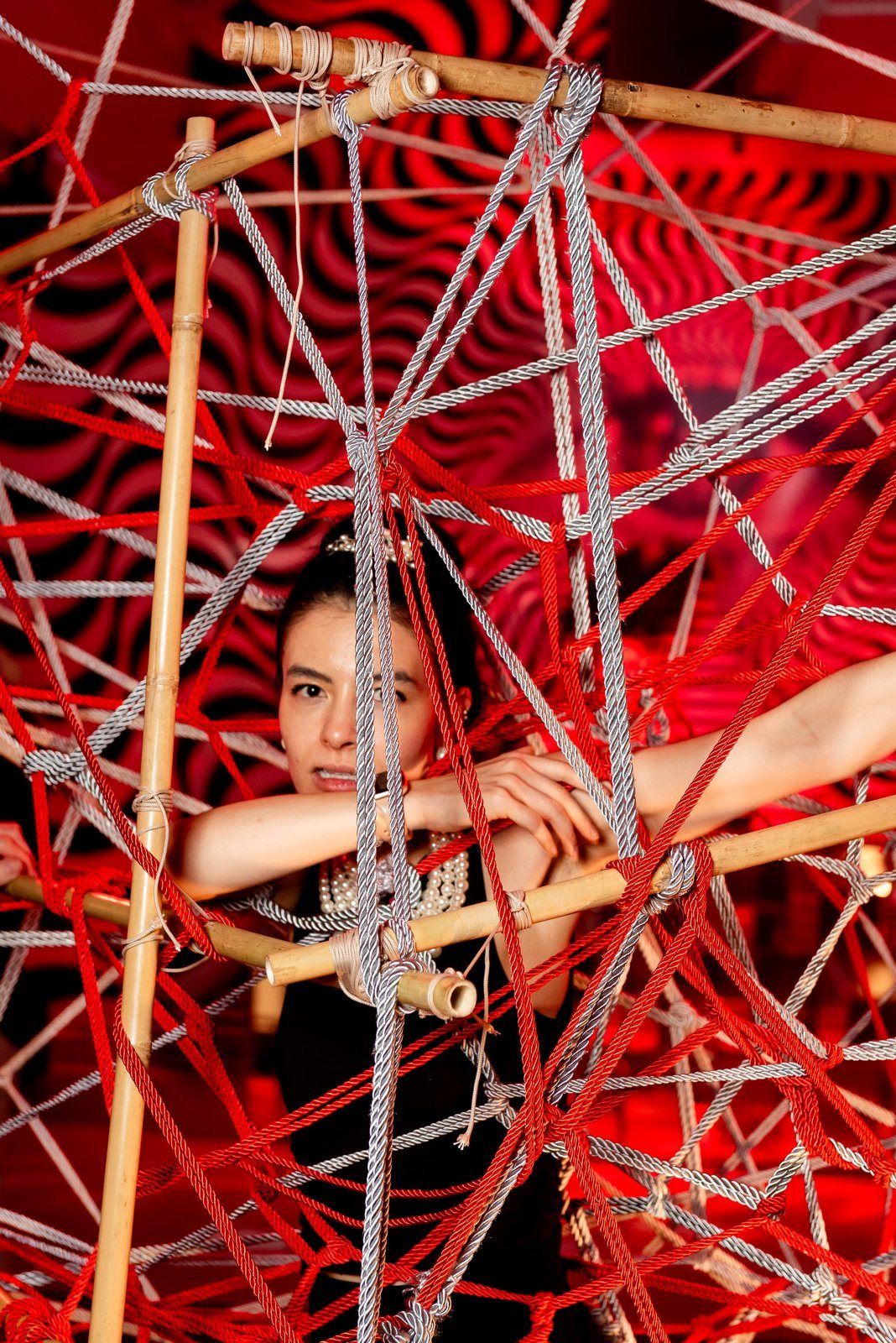 A guest inside a red string installation