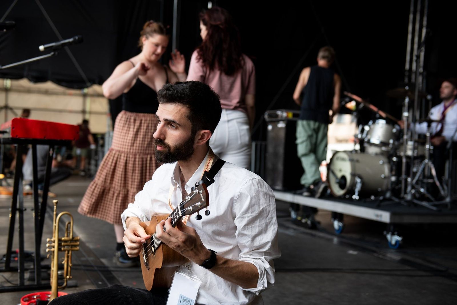 A guitarist playing as band members dance behind him