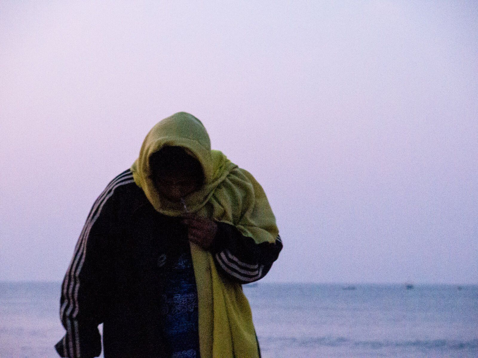 A hooded figure against a lilac sky