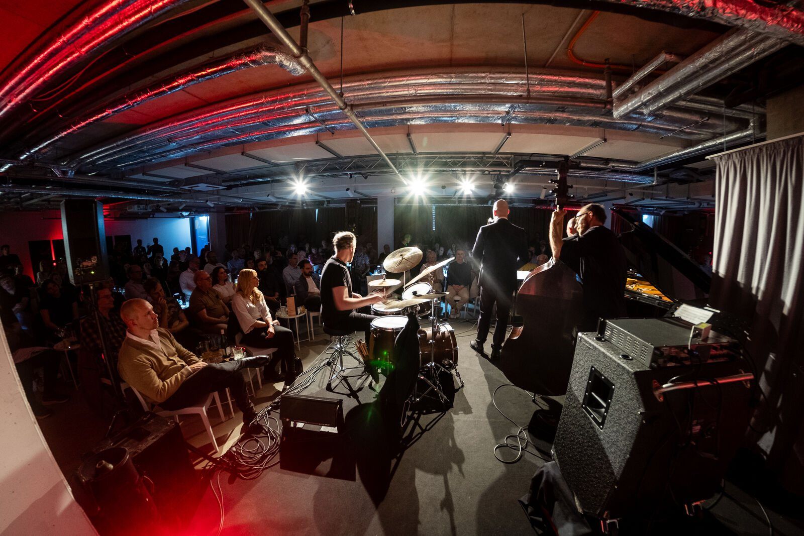 A jazz quintet playing to a full room under red light