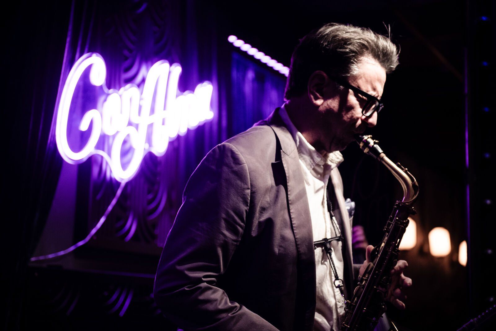 A saxophonist under the Con Alma neon sign