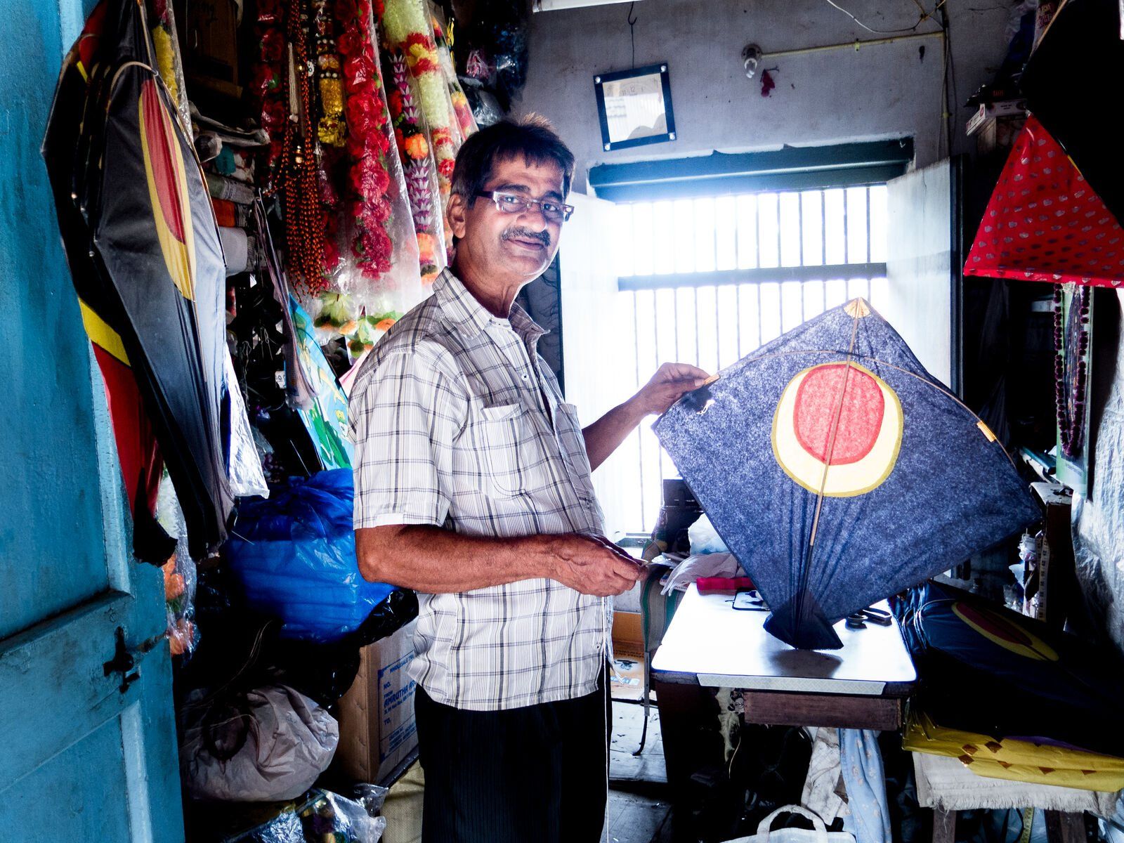 A shopkeeper holding up a kite