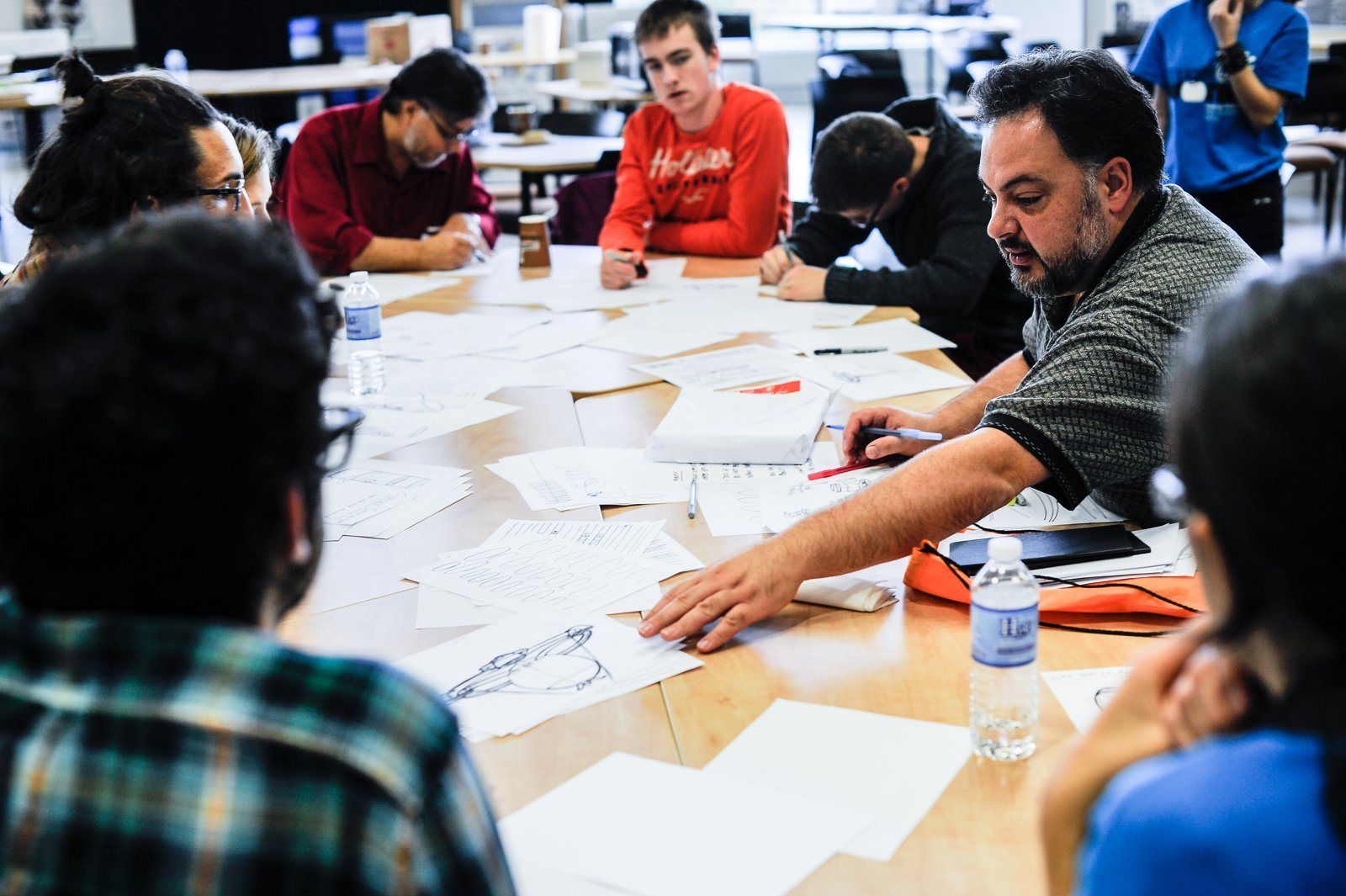 A speaker leaning over sketches with a group of students