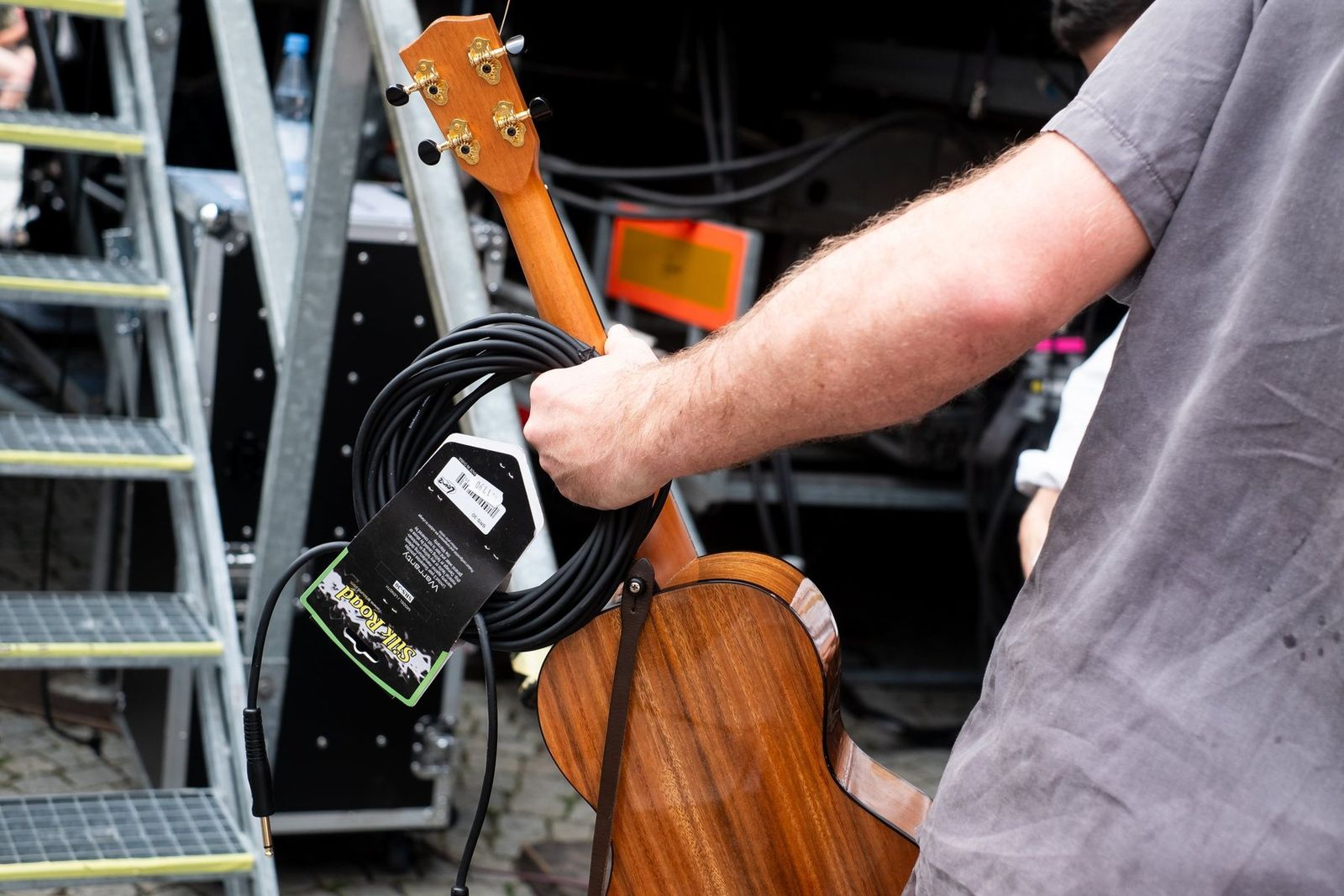 A ukulele and a coiled cable carried up the stage stairs