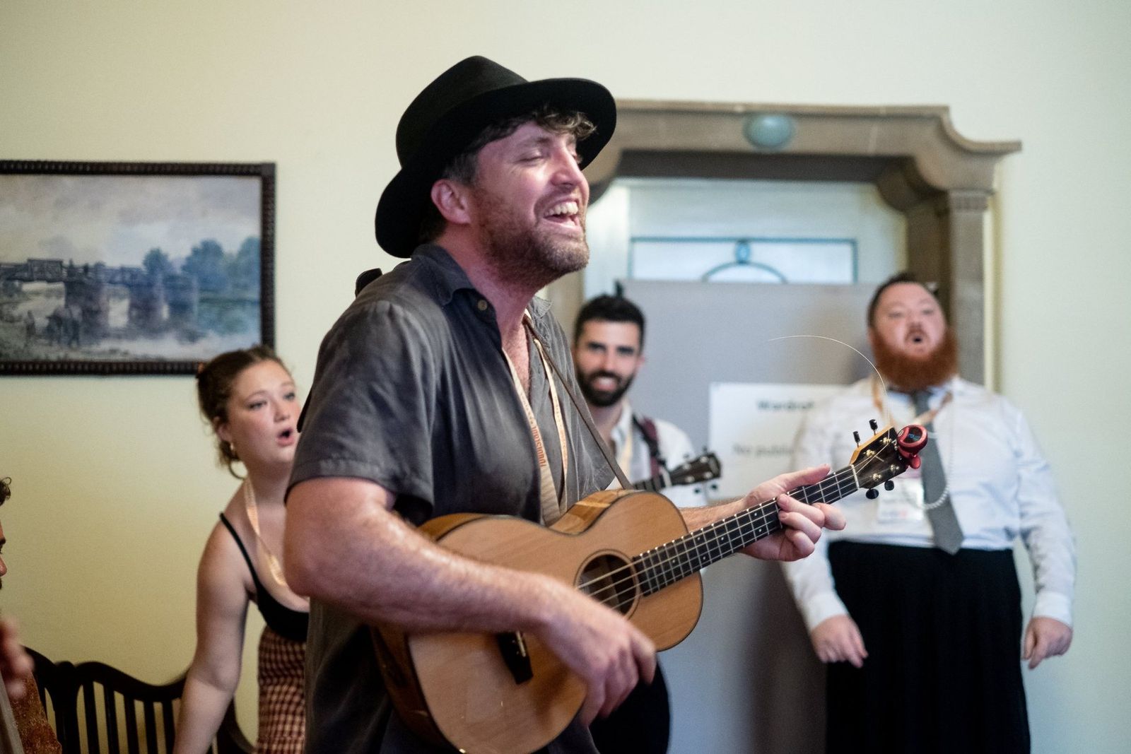 A ukulele player singing with the band in the room where everyone sheltered from the rain
