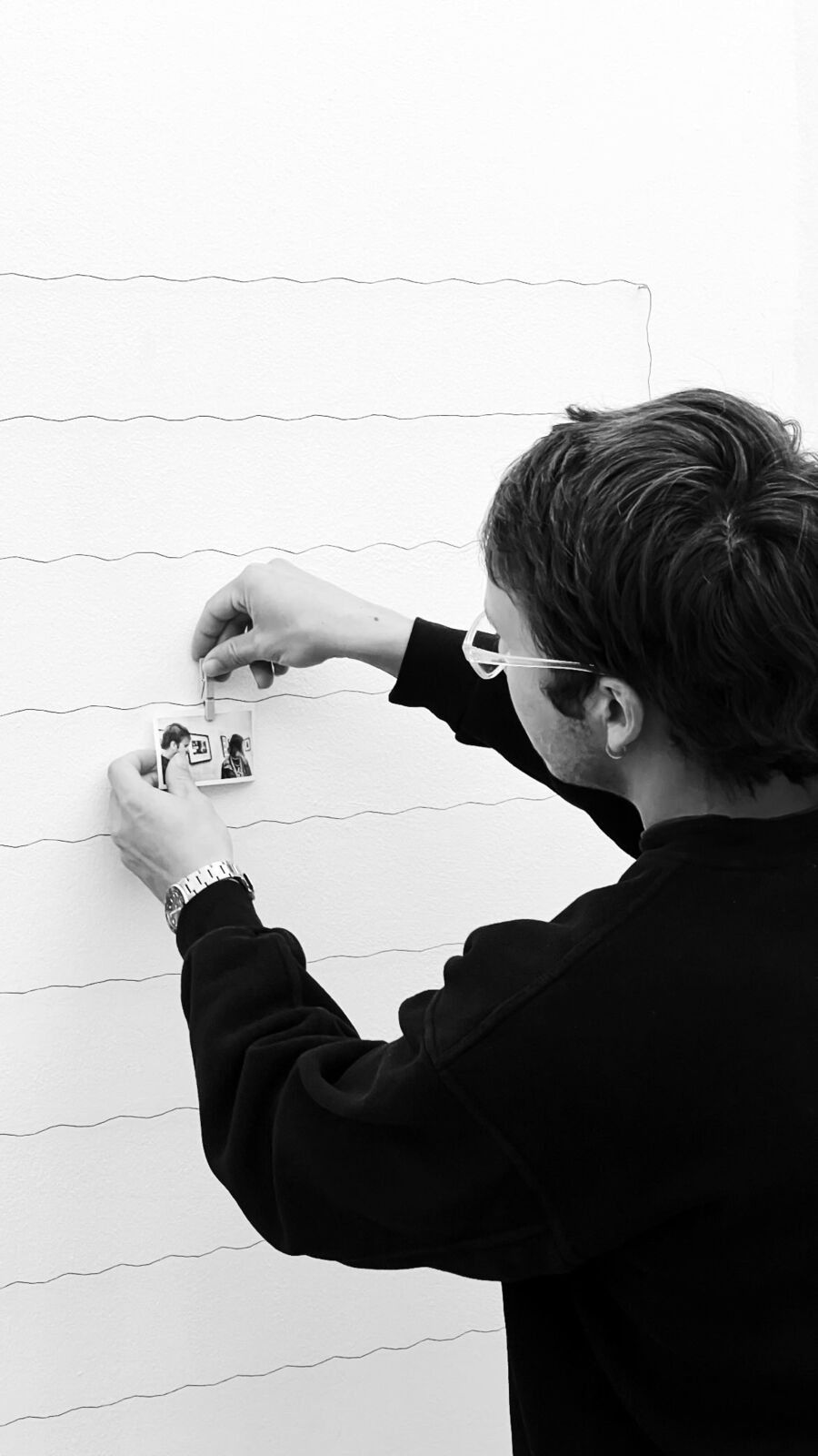A visitor pinning a portrait to the wire wall