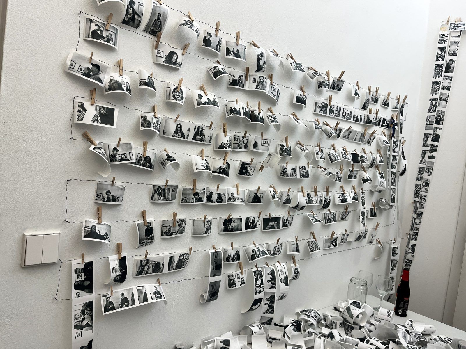 A wire wall hung with hundreds of thermal portrait prints