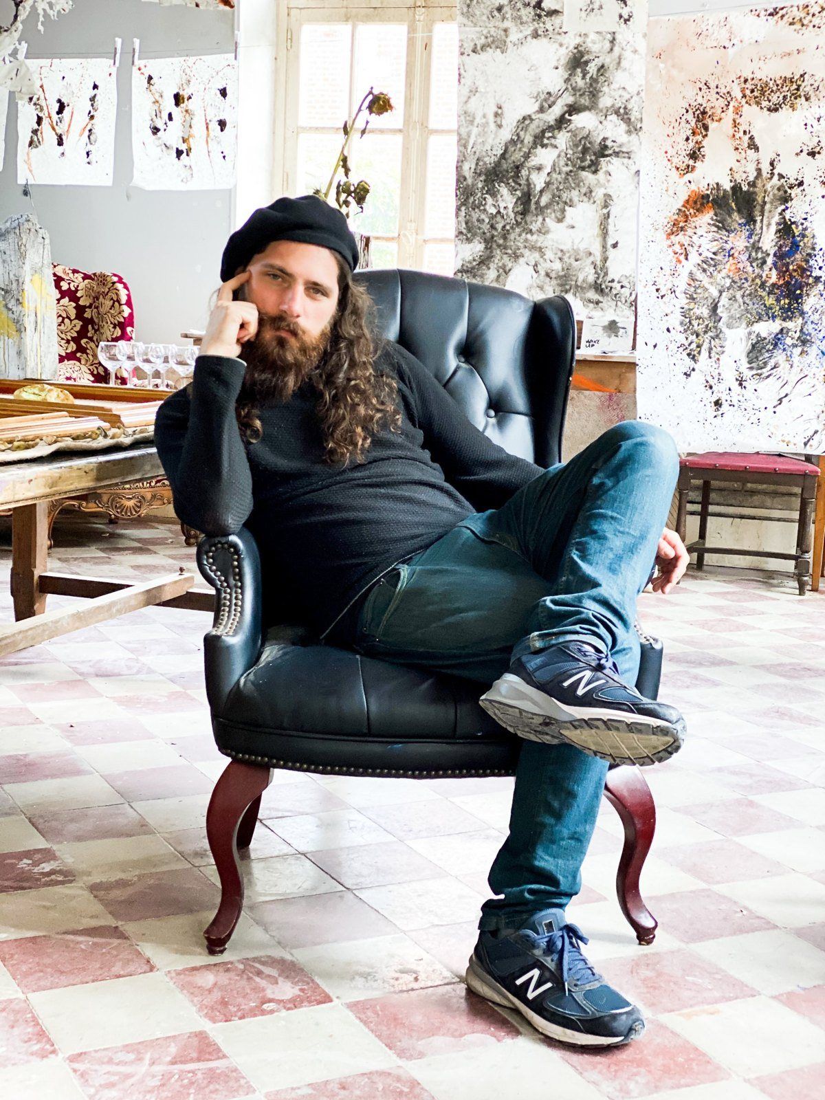 Aaron in a leather armchair in front of large ink paintings