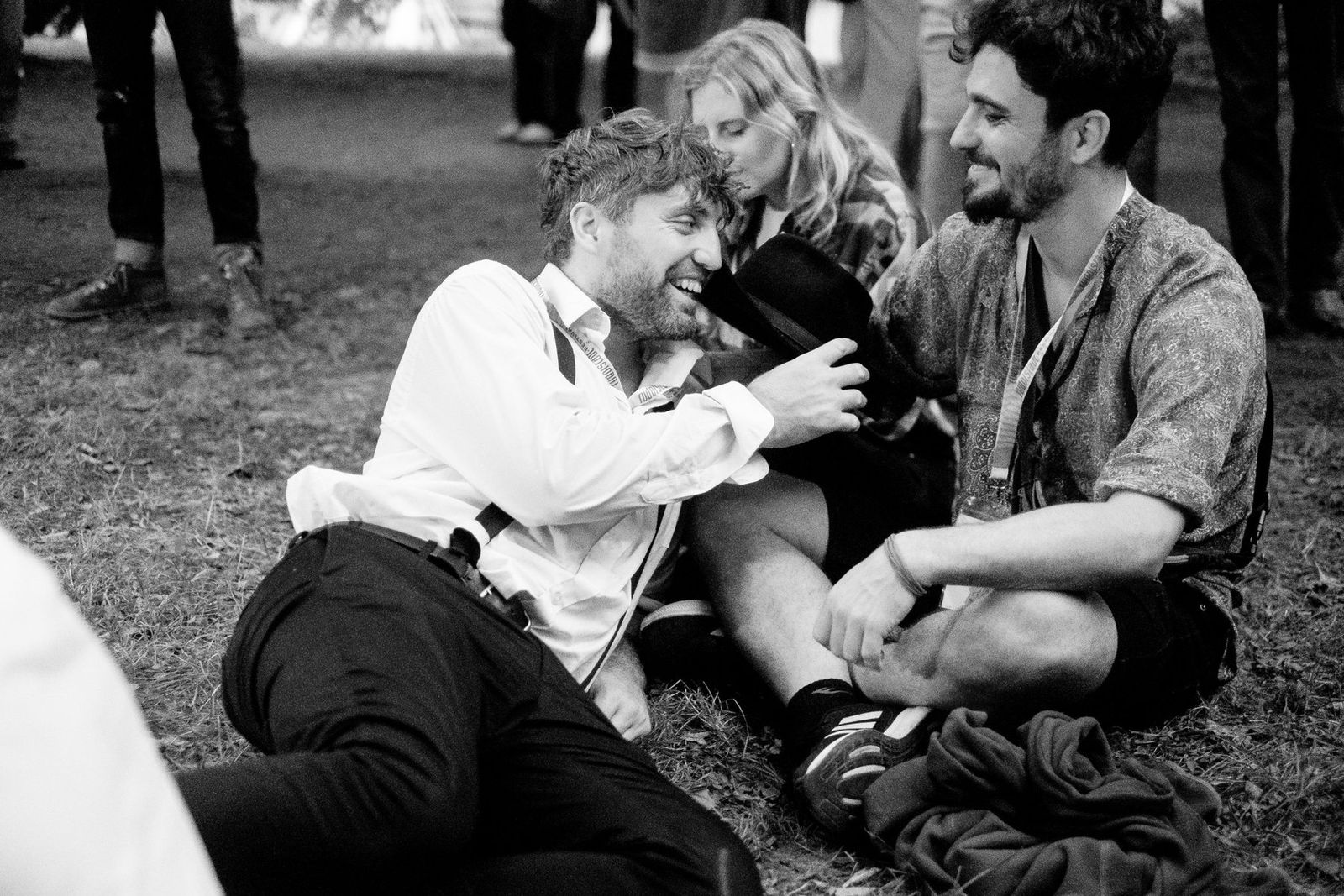 Band members resting on the grass and laughing, black and white