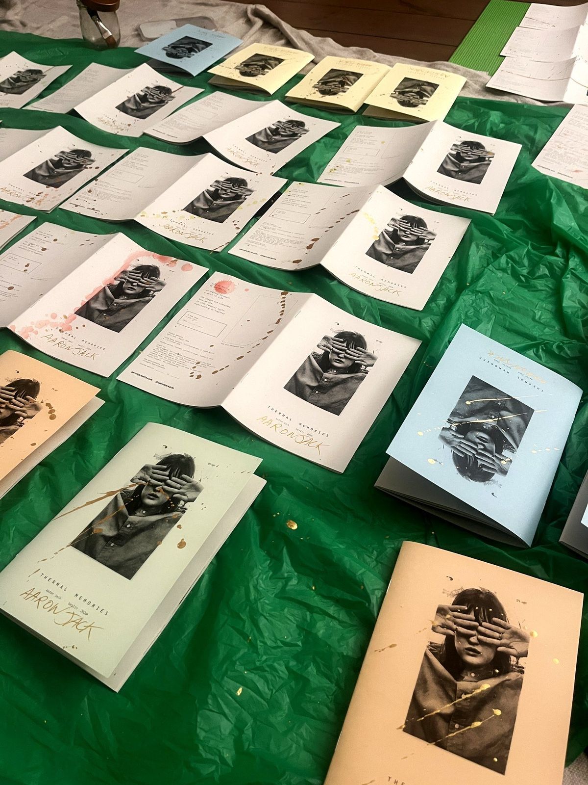 Copies of the book in every cover colour, laid out on a green tarp