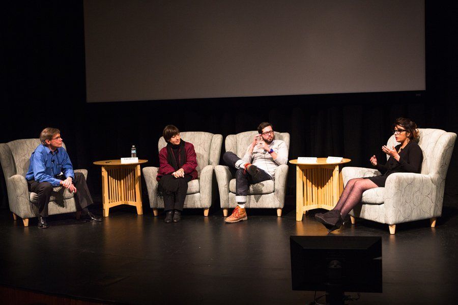 Four speakers in armchairs on stage