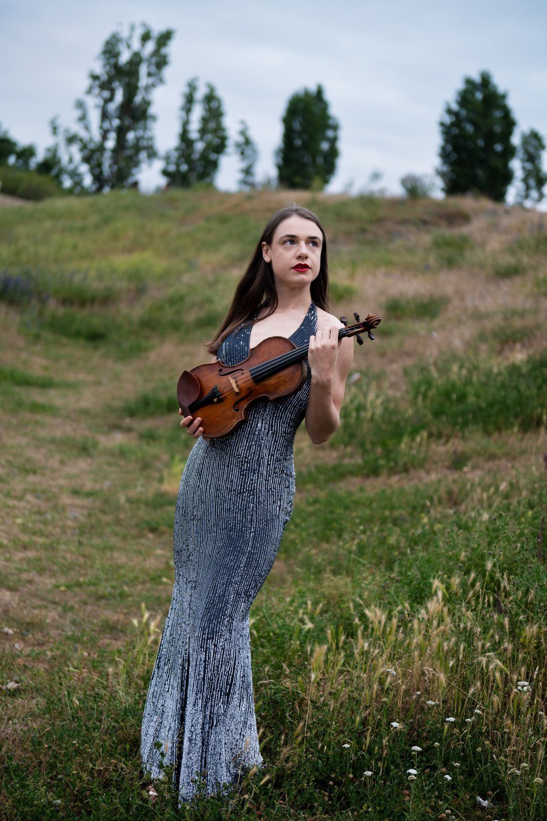 Julia holding her violin on the path through the park