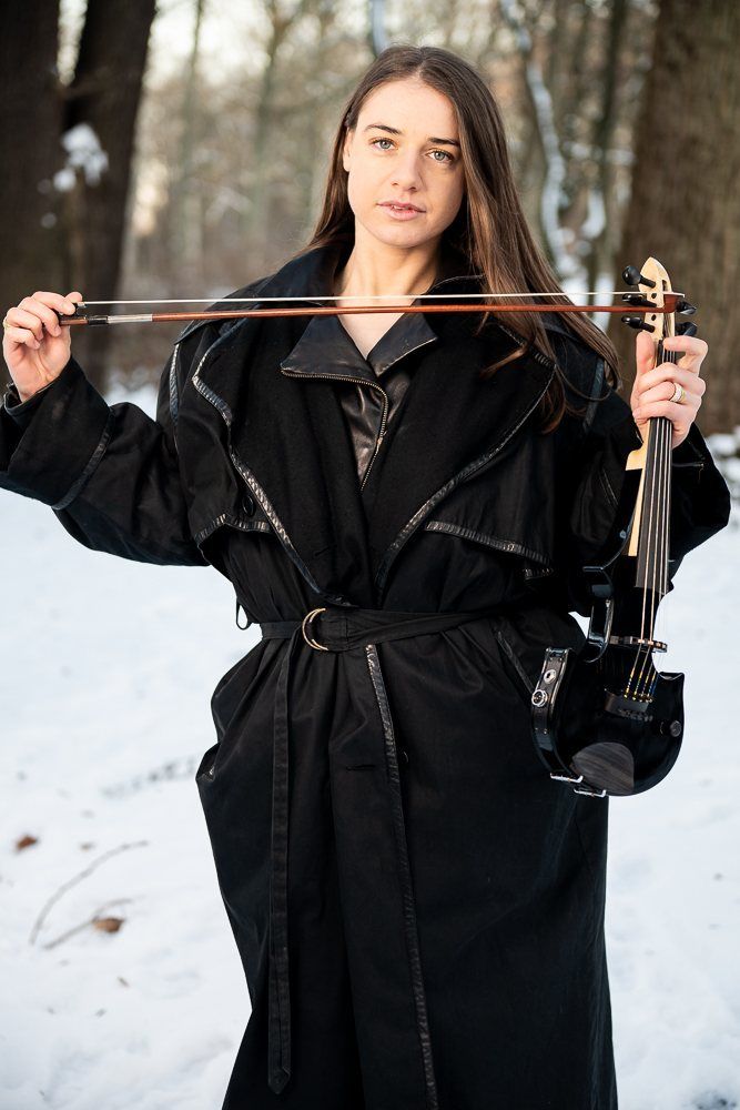 Julia holding the bow out wide, coat open