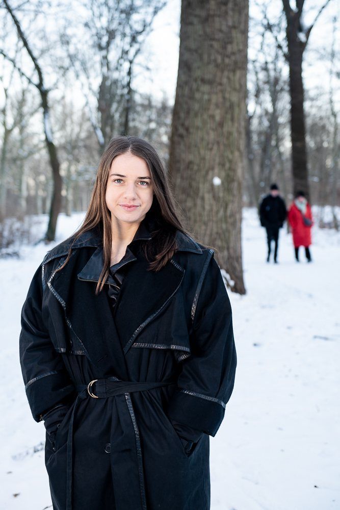 Julia in a belted black coat on a snowy path