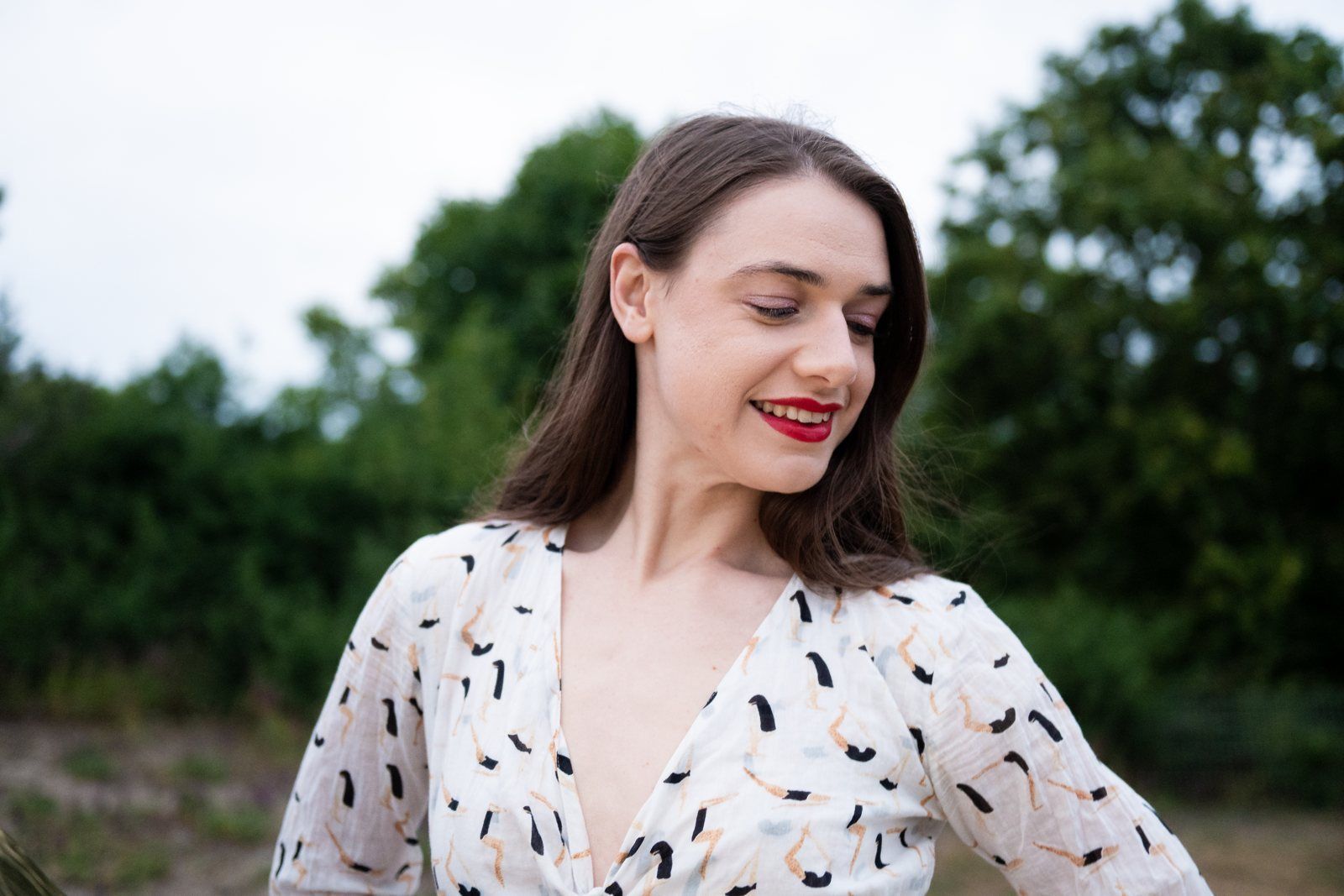 Julia looking down and smiling, in a patterned blouse