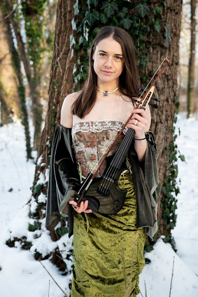 Julia with her violin in front of an ivy-covered tree
