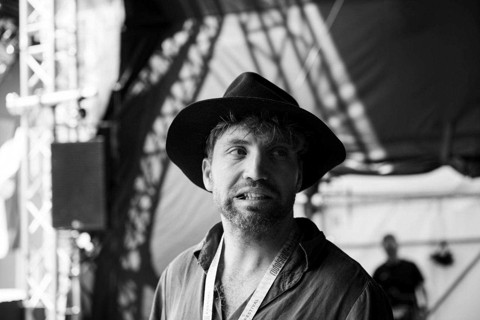 Portrait of a band member in a hat beside the stage, black and white