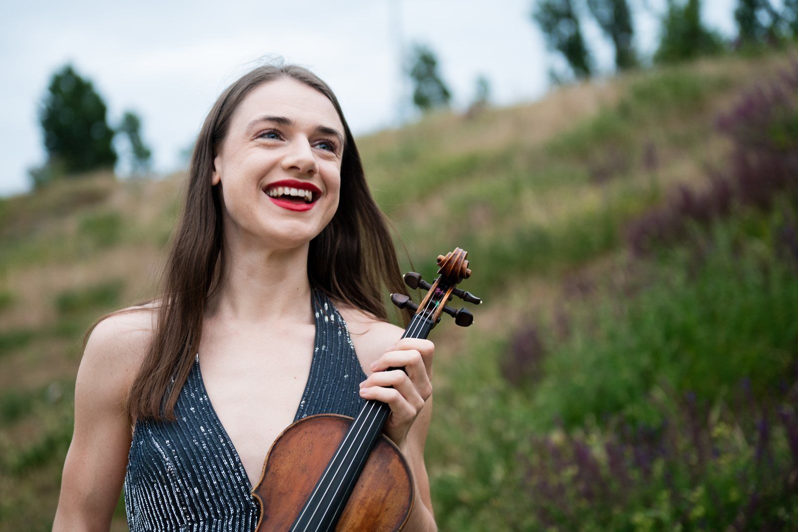 Julia laughing with her violin among wildflowers