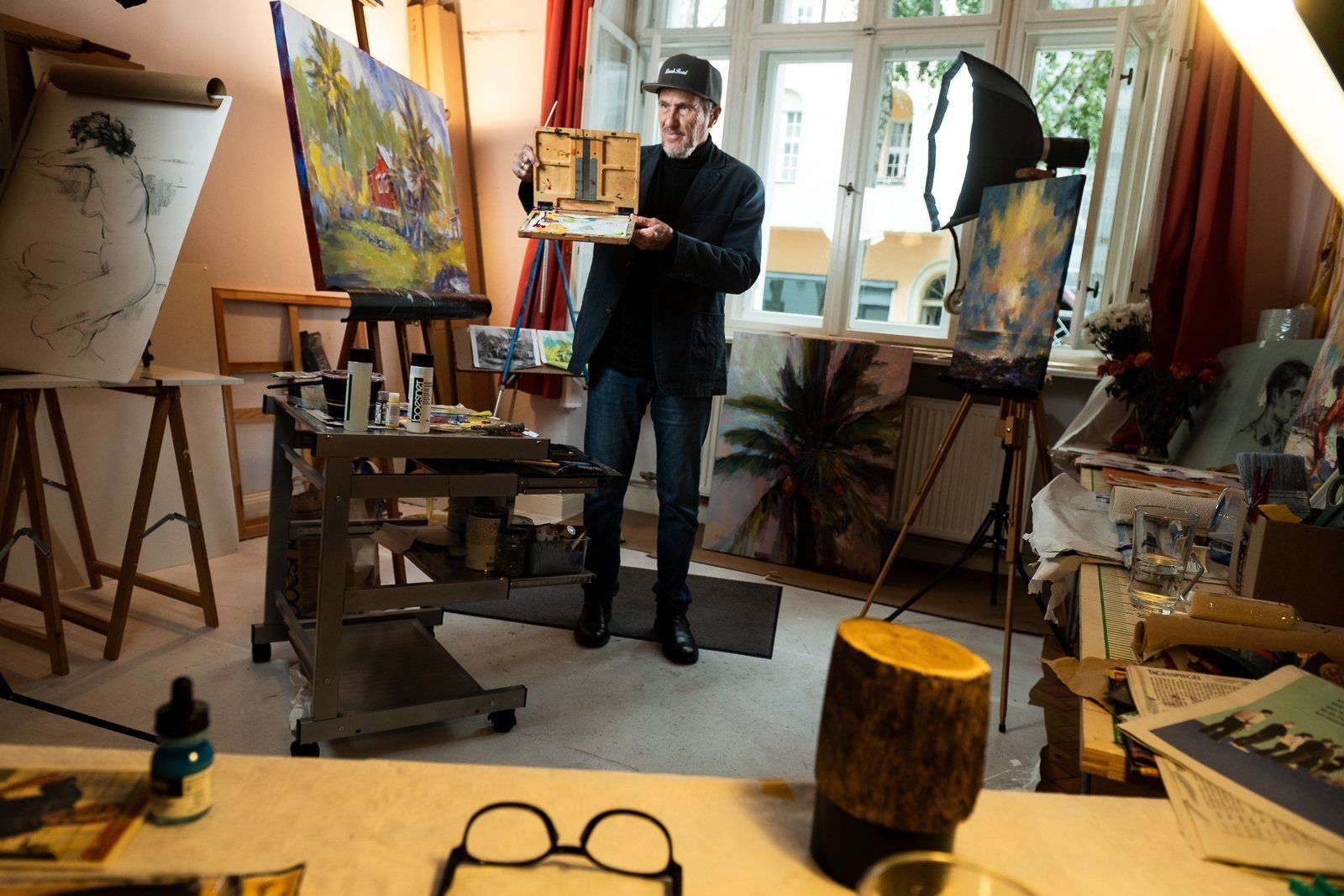 Rod Cameron holding a small painting in his bright studio