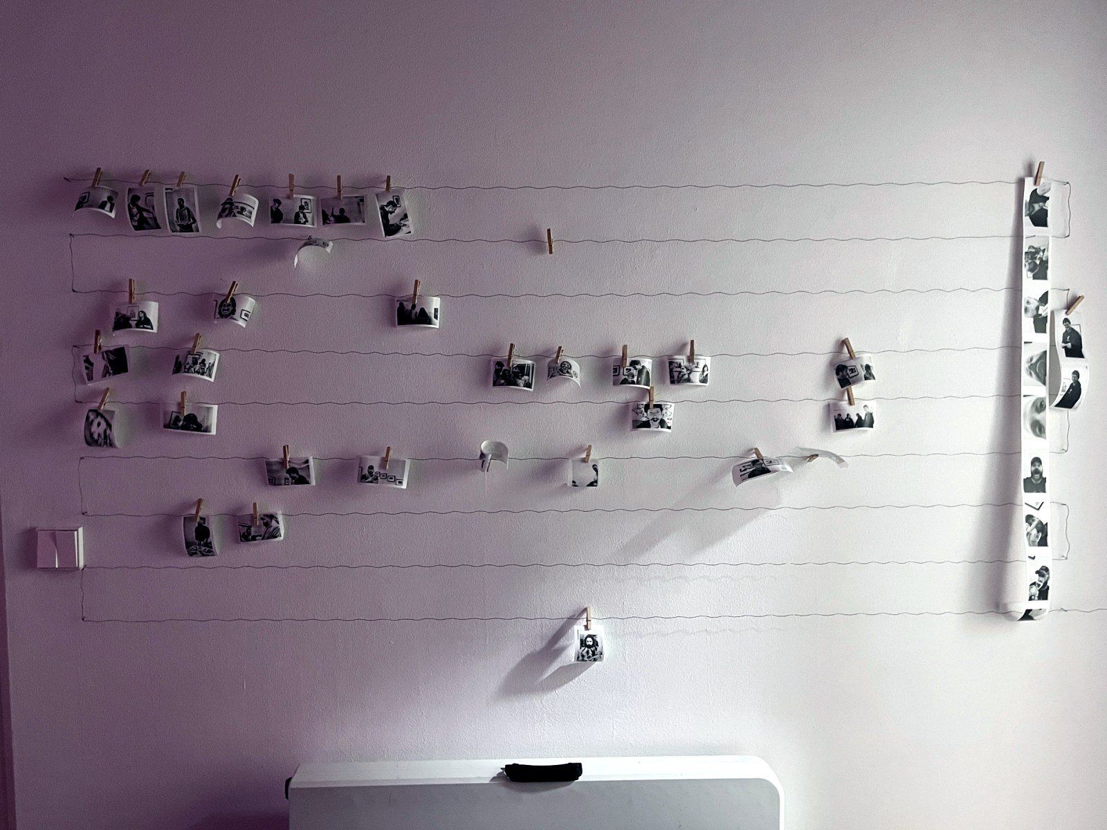 Prints hanging on wires along the wall
