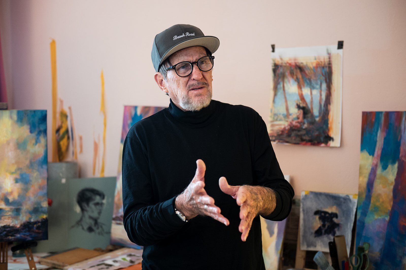 Rod Cameron talking with his hands among his paintings
