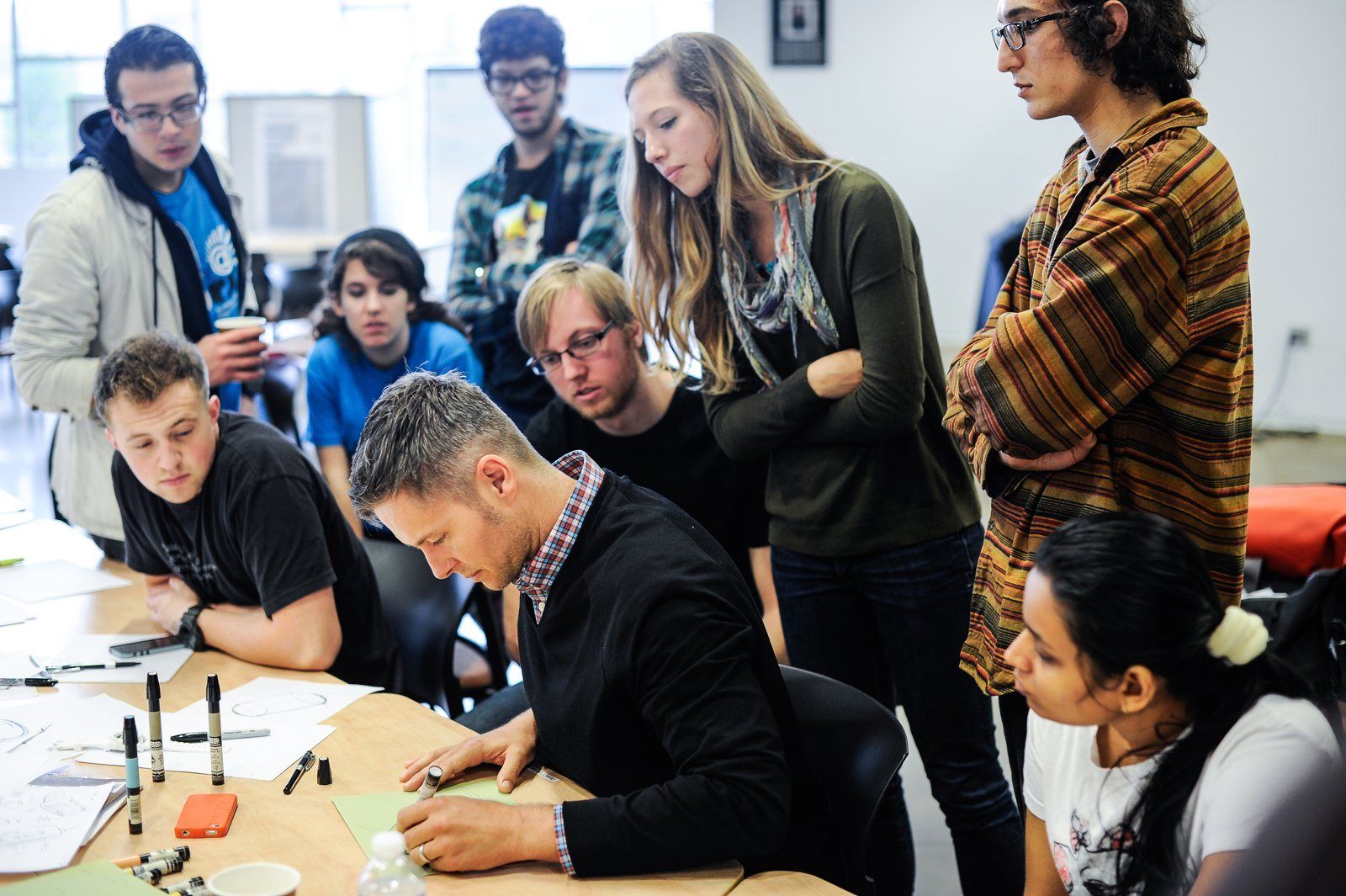 Students and a working designer sketching together at a workshop table