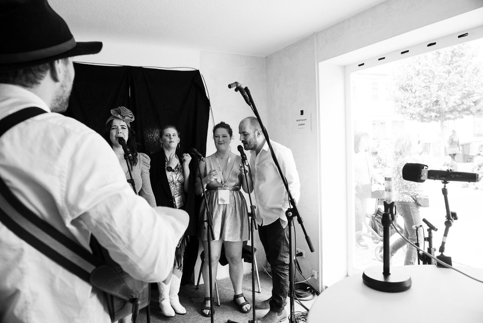 The band playing for the radio, seen past a ukulele player, black and white