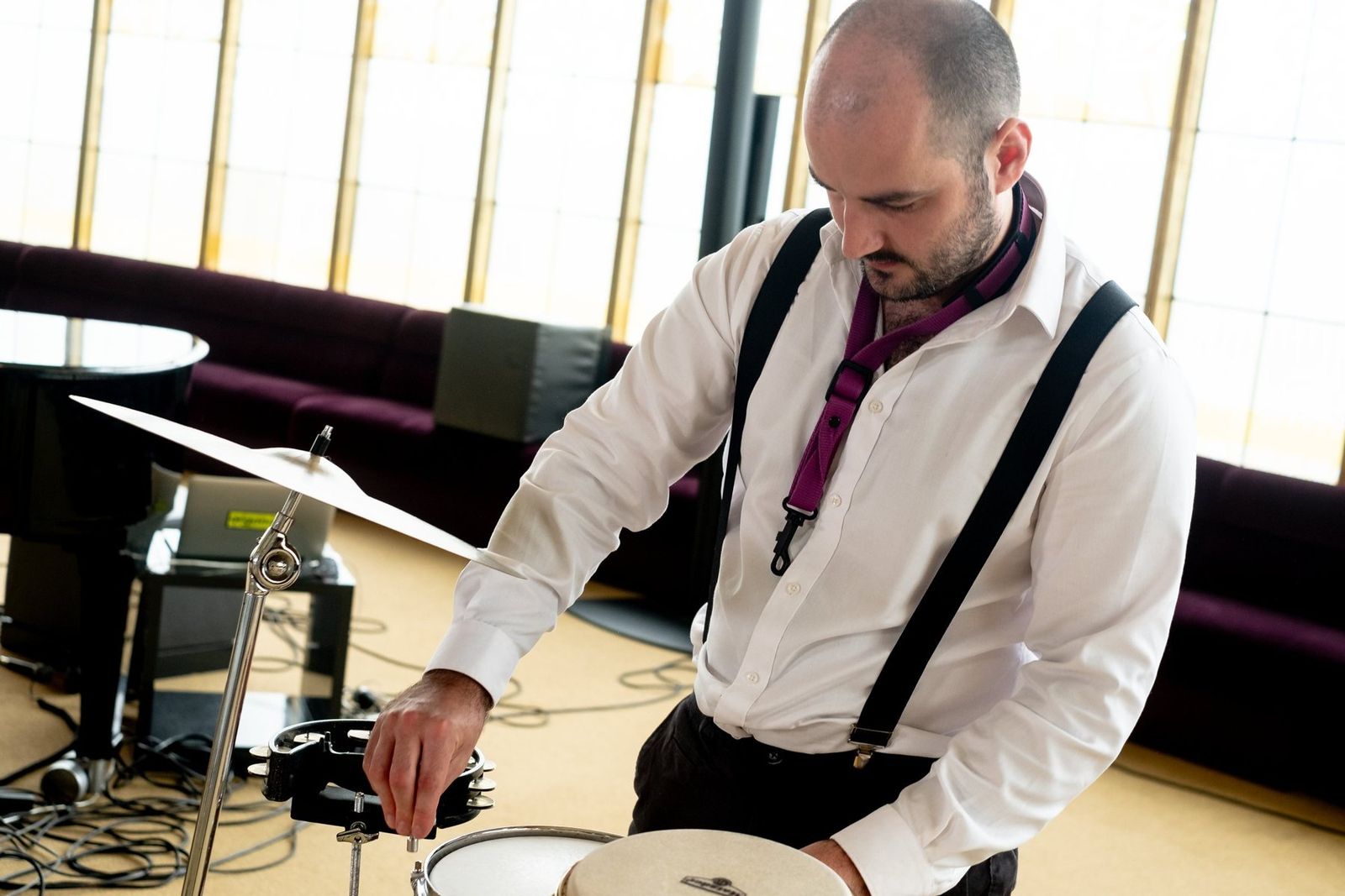 The drummer setting up his kit beside the grand piano