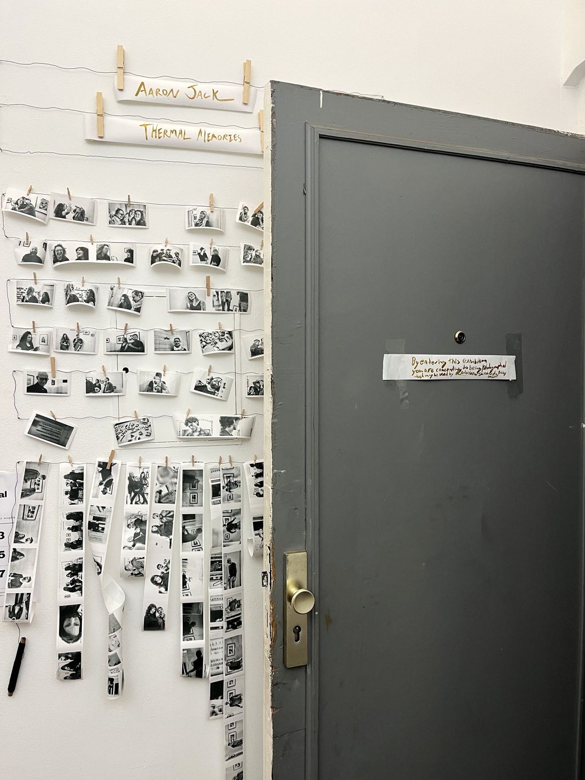 The gallery door with the handwritten gold sign, beside the wall of portraits