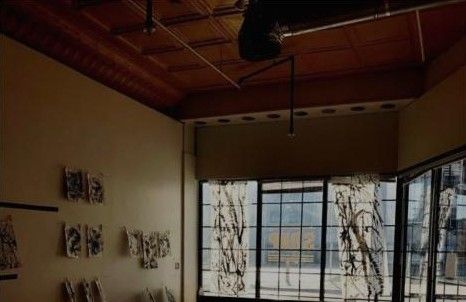 The gallery room with ink paintings on the walls and painted strips in the windows