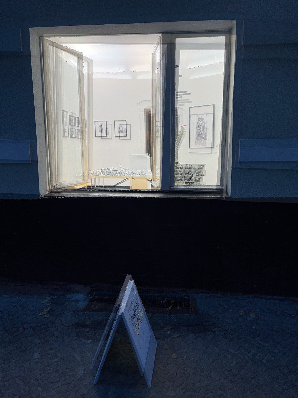 The lit gallery window at dusk