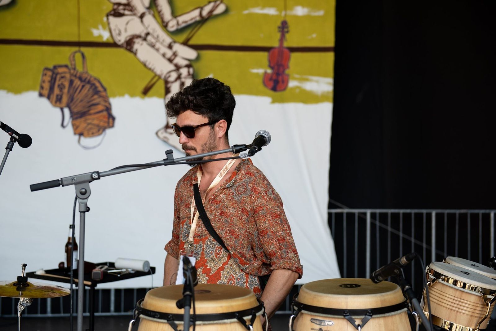 The percussionist at the congas during soundcheck, the festival backdrop behind him