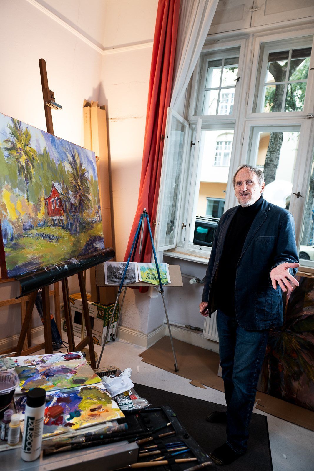 Rod Cameron’s studio with tall windows and red curtains