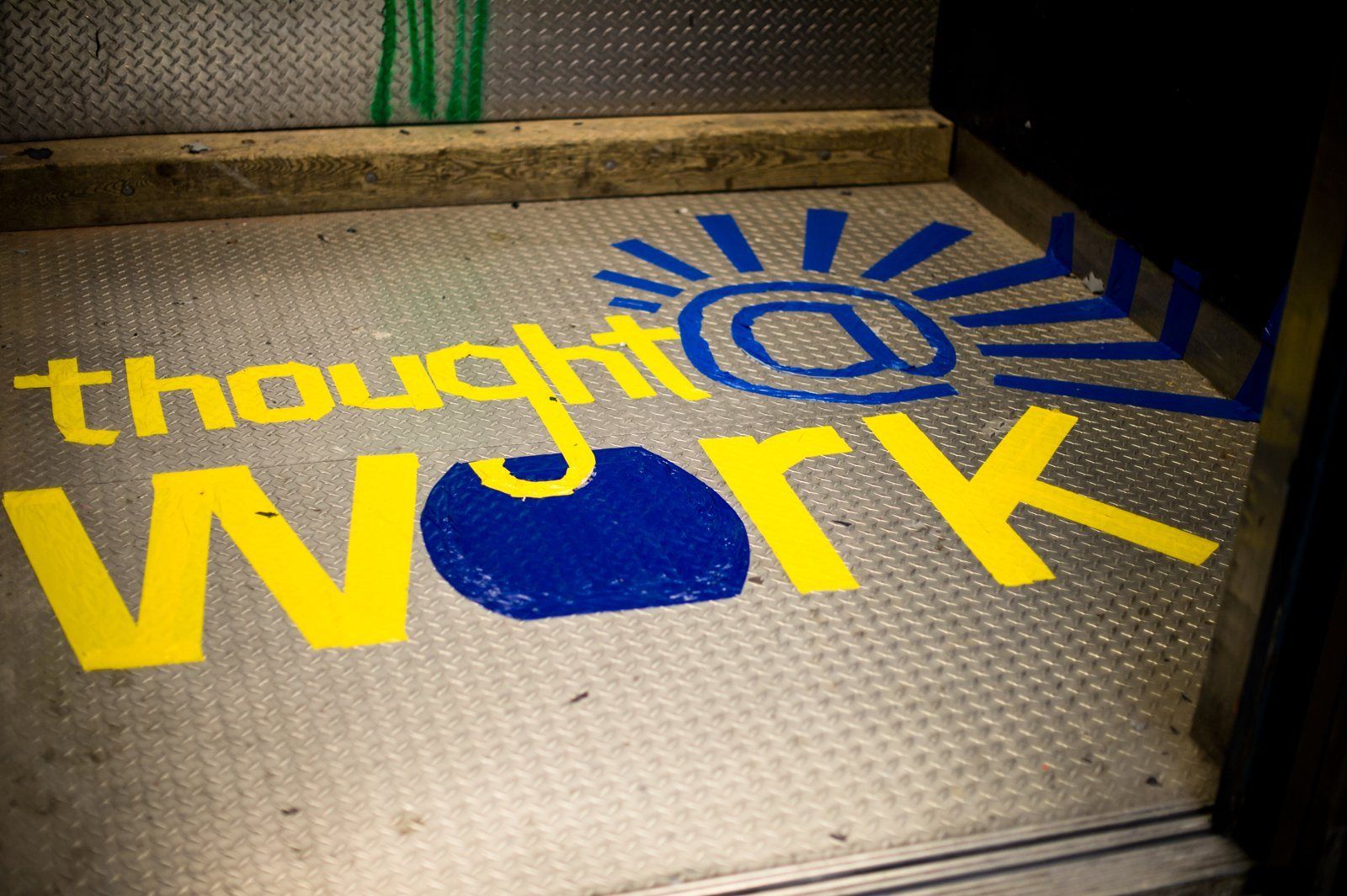 The Thought at Work logo painted on the floor in yellow and blue