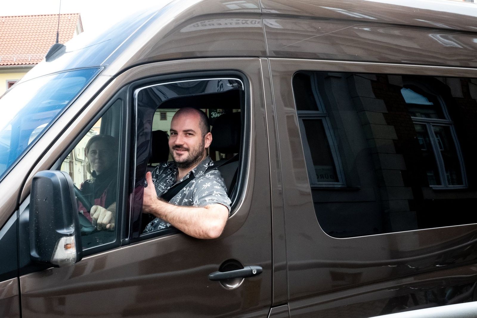 The tour van pulling in, the driver giving a thumbs up through the window