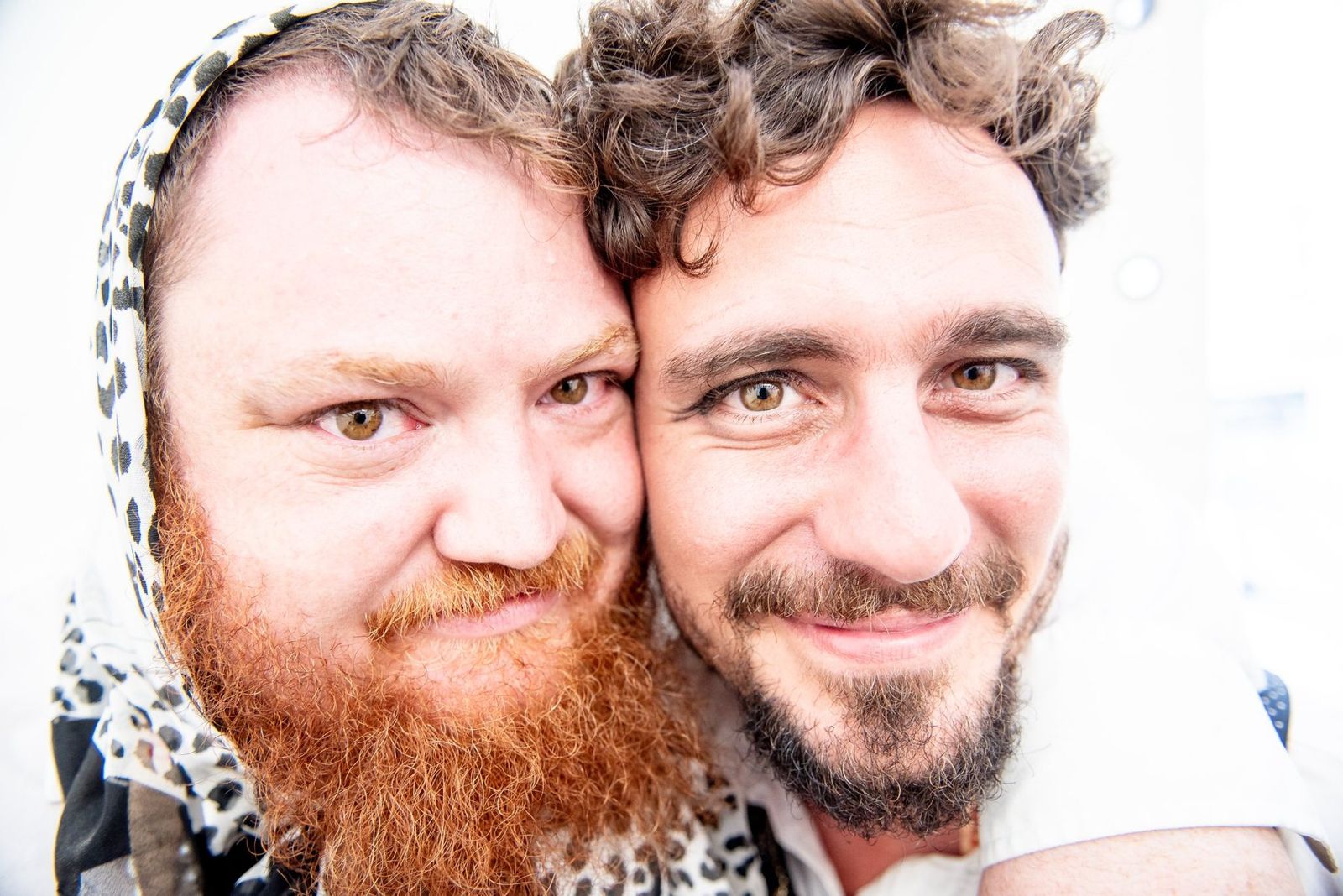 Two band members cheek to cheek, grinning at the camera