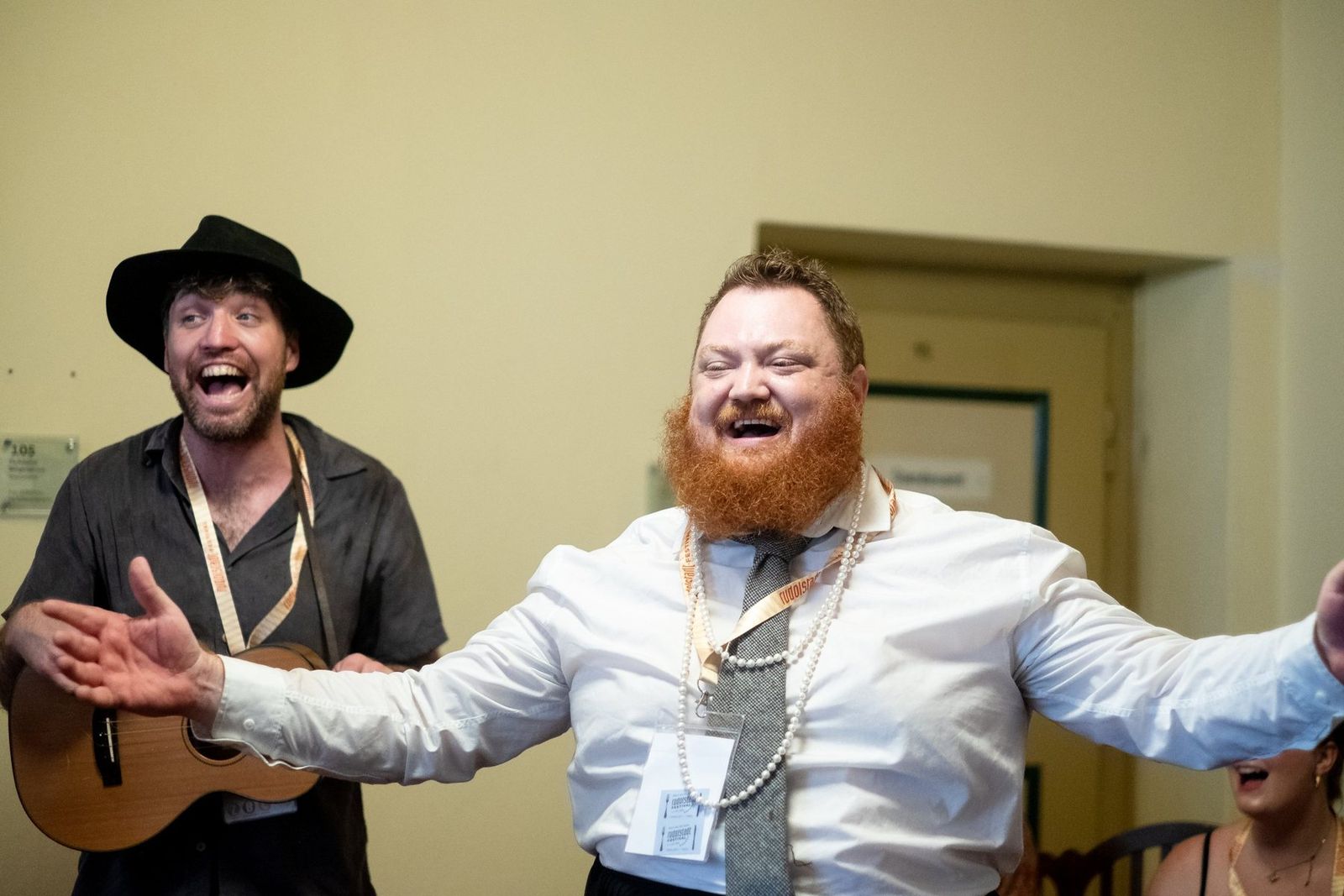 Two band members playing for the room, one with his arms thrown wide, laughing
