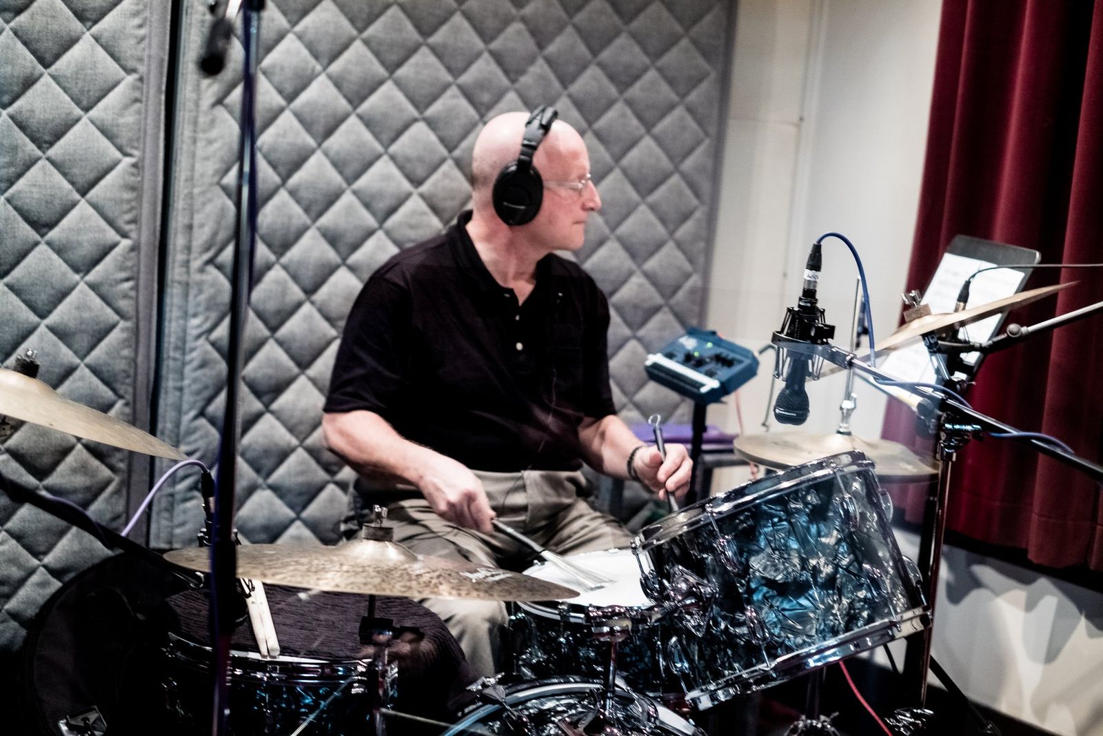 A drummer recording in a padded studio